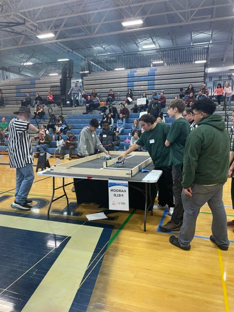 Image of high school students wearing green shirts competing in a robotics compeition