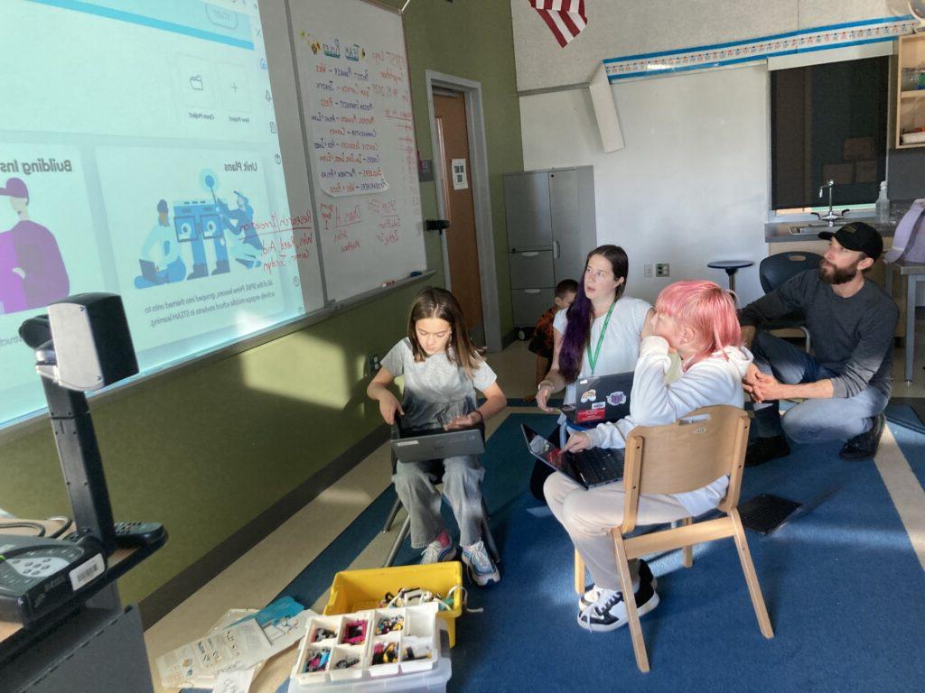 two students and two teachers working together on coding a robot for first lego robotics league. 